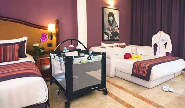 Two beds and a crib in a spacious suite