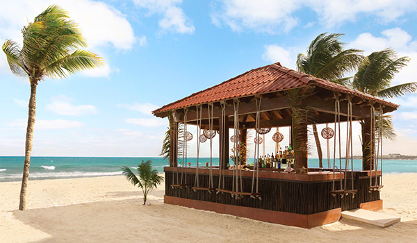 Tiny wooden bar with swing chairs located on the beach.