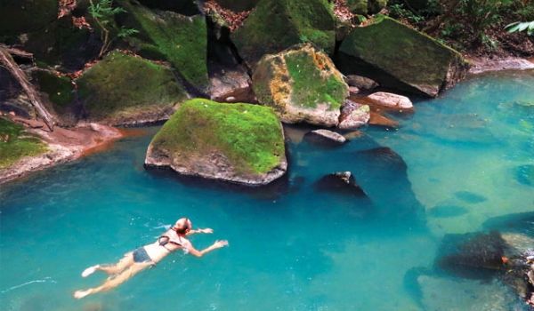 Woman swimming through crystal-clear natural pool