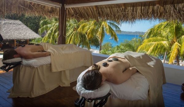 Man and woman enjoying hot stone treatment with views of the ocean