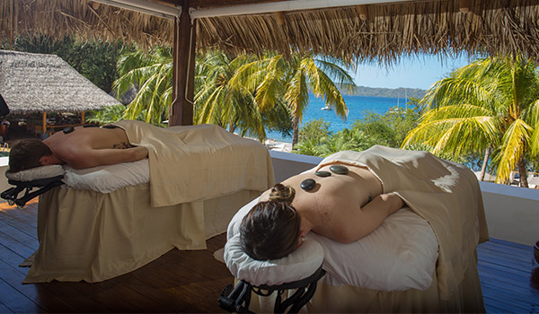 Homme et femme recevant un soin aux pierres chaudes devant la mer