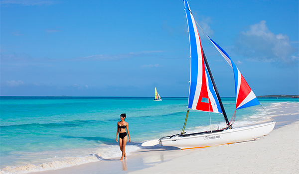 Woman walking by a catamaran beached on the shore