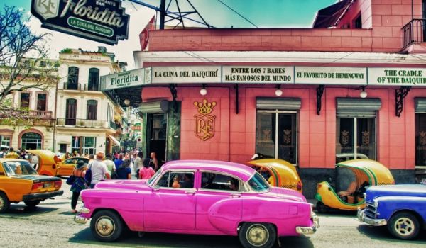 Pink vintage car driving down the streets of Havana