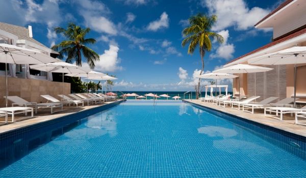 Sparkling pool lined with white lounge chairs and umbrellas