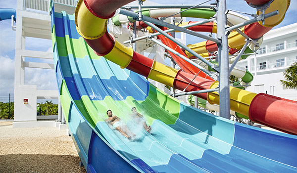 Two people sliding down a water slide