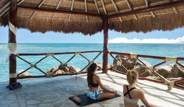 Two women practicing yoga in an oceanside gazebo