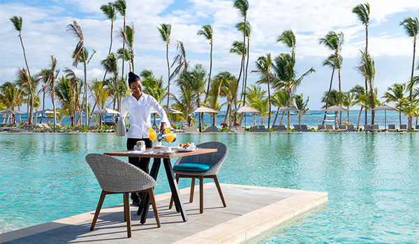 Waiter pouring mimosas at a breakfast table in the middle of the pool
