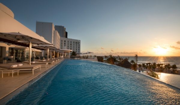 Infinity pool overlooking white-sand beach at sunset