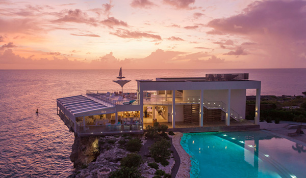 Restaurant perched on a cliffside overlooking the ocean with a pool