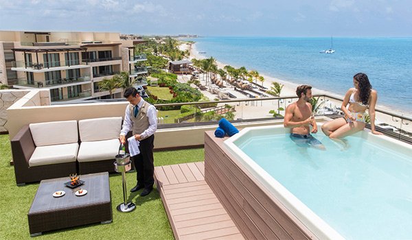 Couple sitting in a rooftop Jacuzzi overlooking the ocean while butler pours them champagne