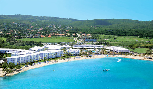 Aerial view of a hotel set along a beach with hills in the background