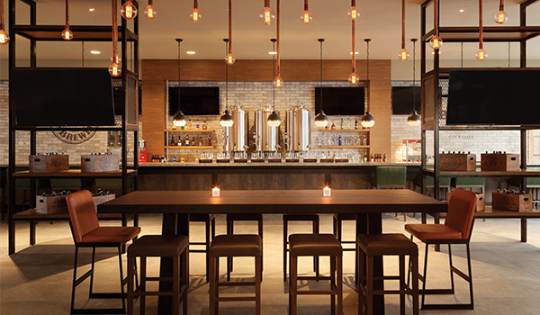 Trendy bar area with string lights, beer taps and a rectangular table with chairs.