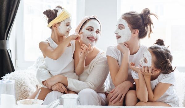 Woman and three young girls enjoying face mask treatment