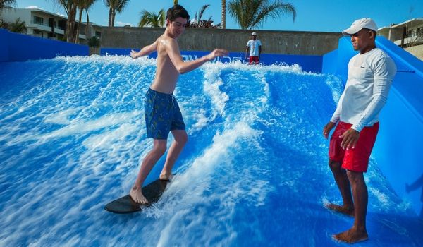 Un homme apprenant à un garçon comment surfer sur le FlowRider
