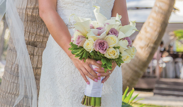 Bride holding a bouquet of purple roses and alcatraces