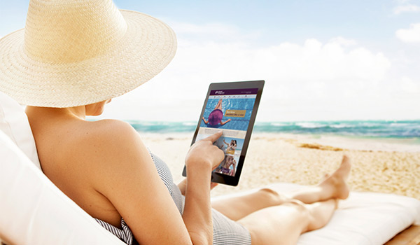 Woman sitting on a luxurious beach lounger reading an iPad