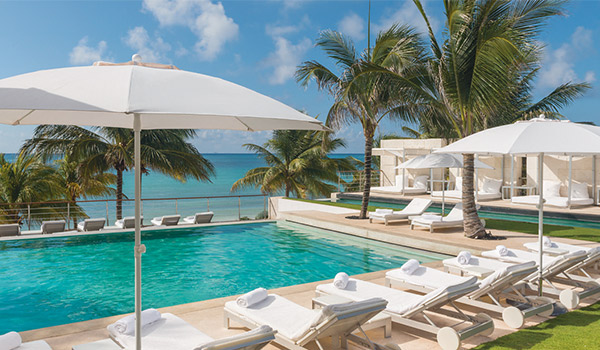 Piscine entourée de chaises longues confortables donnant sur la plage