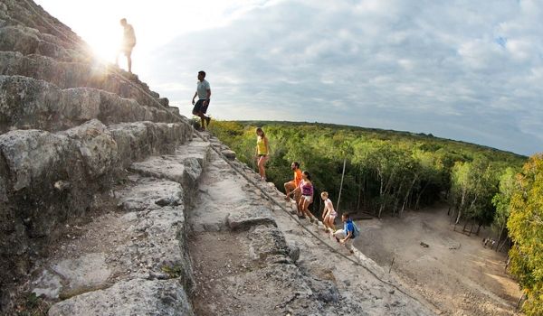 People climbing the steep ruins of a Mayan ruin