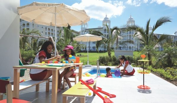 Kids sitting by a mini pool with resort staff playing games