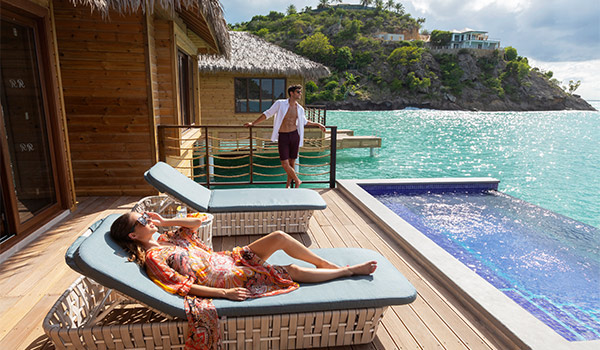 Couple lounging on the pool deck of their overwater bungalow