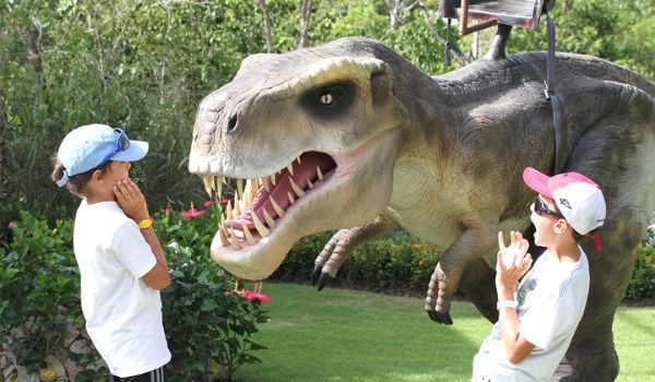 Deux enfants à côté d’un Tyrannosaure Rex anamatronique