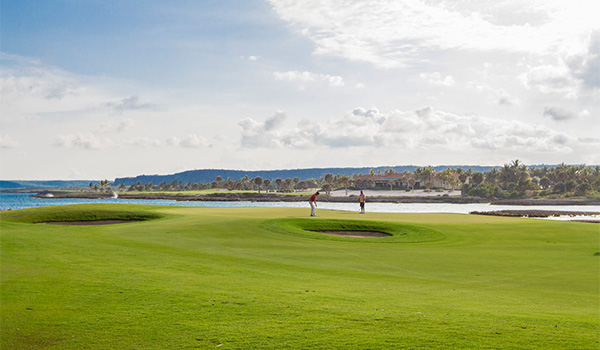 Two people playing golf on a course overlooking the ocean