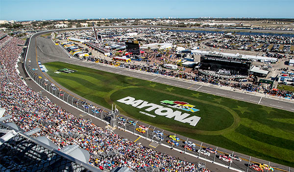Aerial view of the Daytona Internal Speedway with colourful race cars and hundreds of spectators.