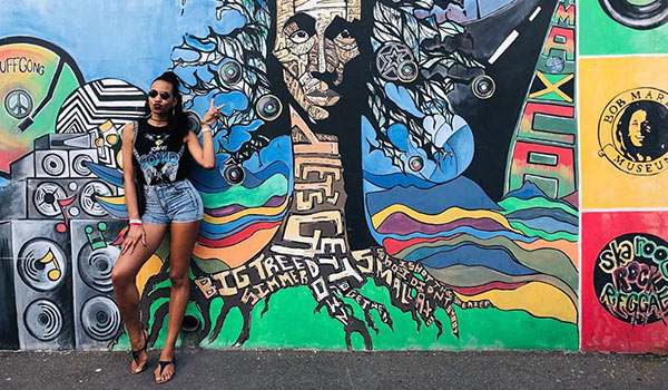 Girl posing in front of a Bob Marley mural