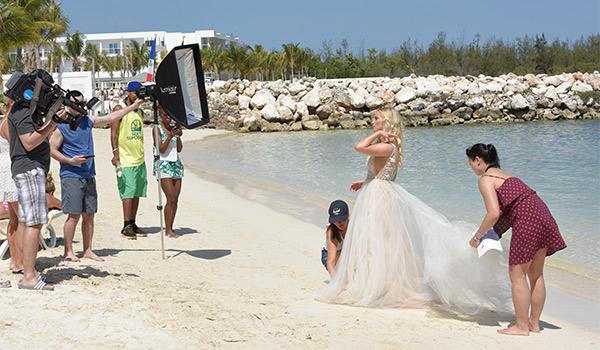 Liz having her photo taken on the beach surrounded by a production crew