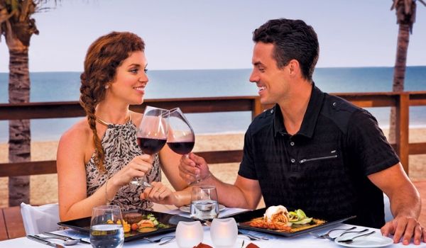 Couple toasting with glasses of wine overlooking the beach