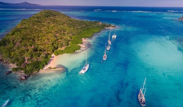 Aerial view of boats cruising past Tobago with the turquoise sea
