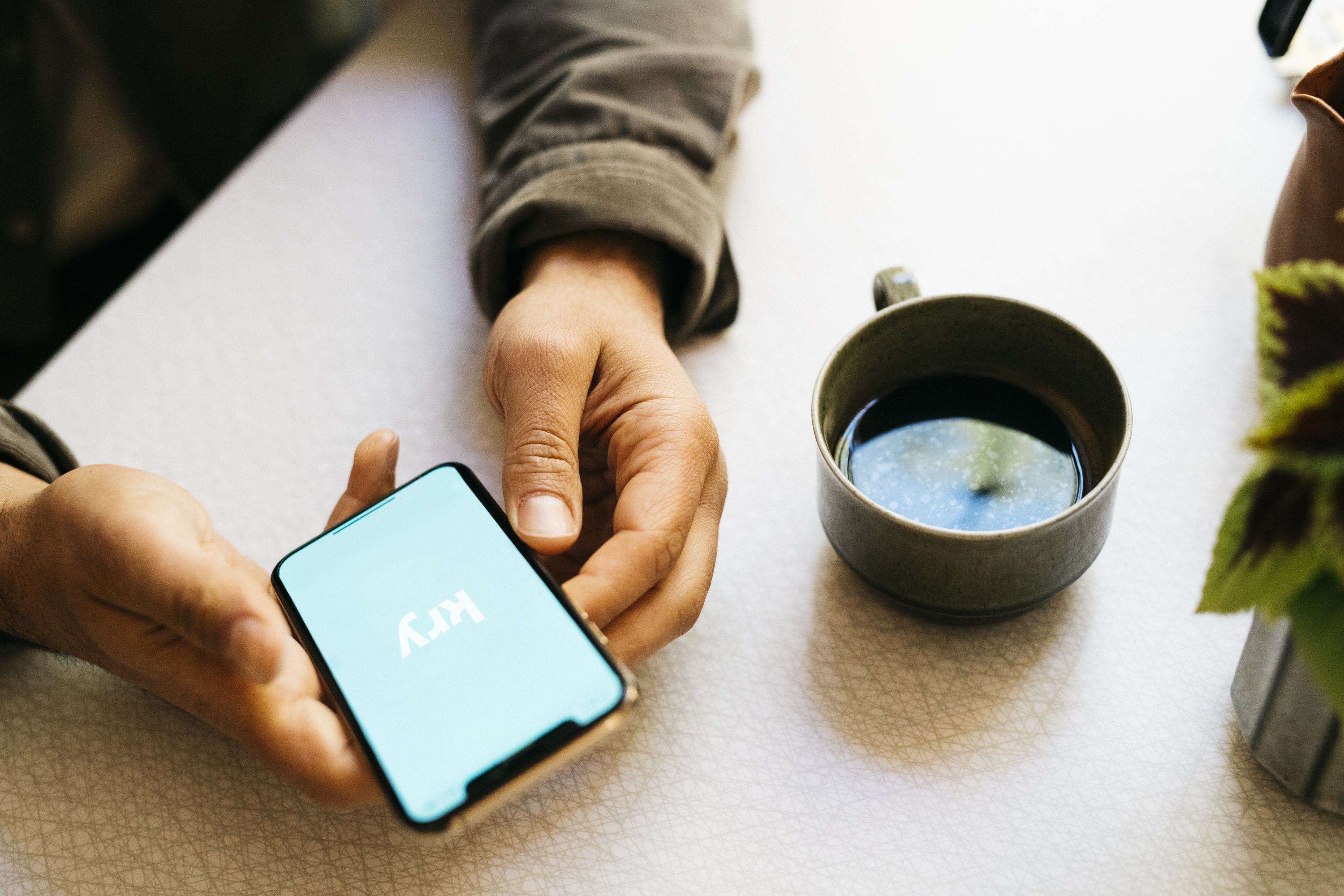 Hånd med telefon logget inn i Kry-appen