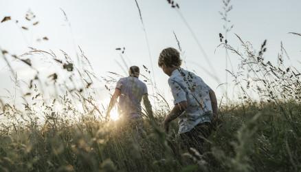 Un homme et un enfant marchant dans les hautes herbes