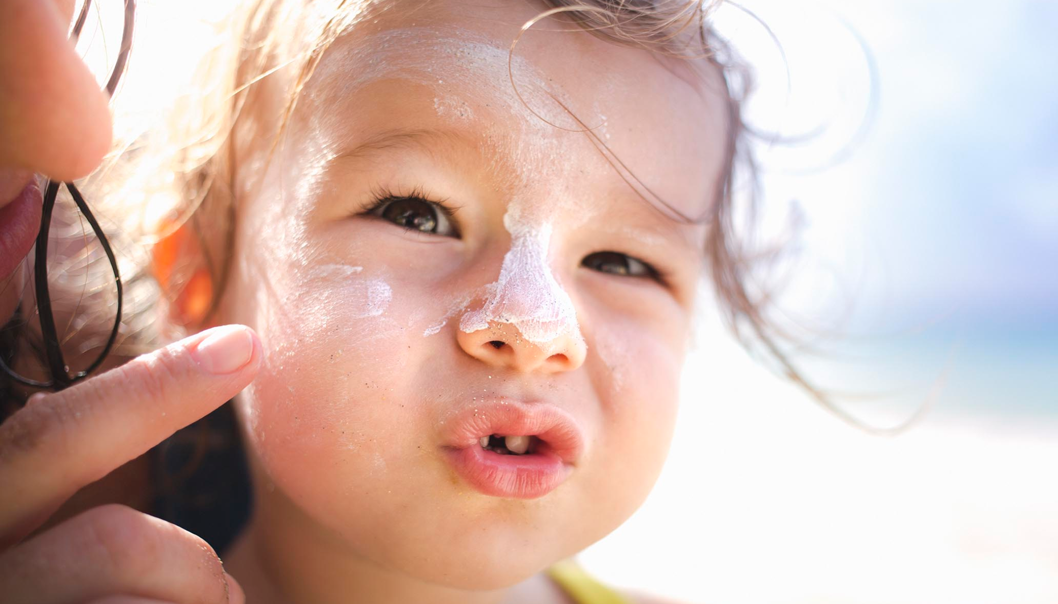 Bilde av et lite barn med solkrem i ansiktet