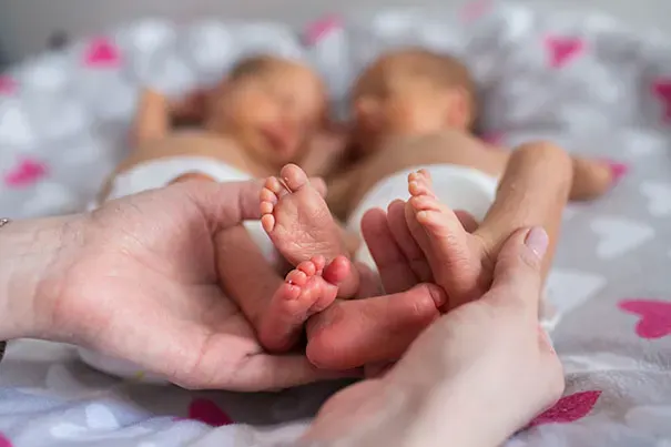 Parent holds the feet of newborn twins