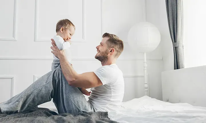 Banner Image of Father Playing with Baby for Article on 23 Baby Games to Play with Your Baby