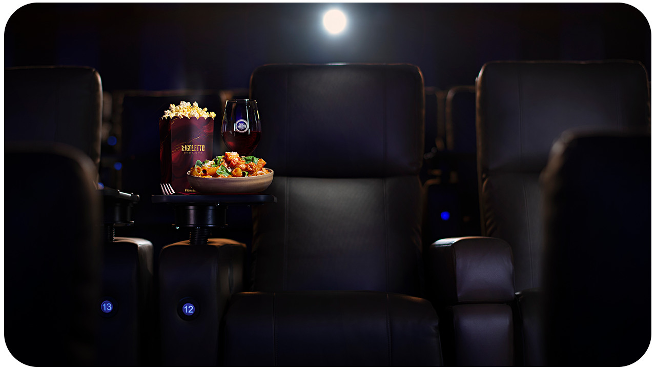 Bild på Luxe-stol i biosoalong, med mat, dryck och popcorn på lite bord.