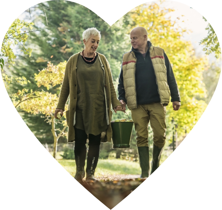 Actor portrayals of a woman and man walking in an apple orchard in a heart shape