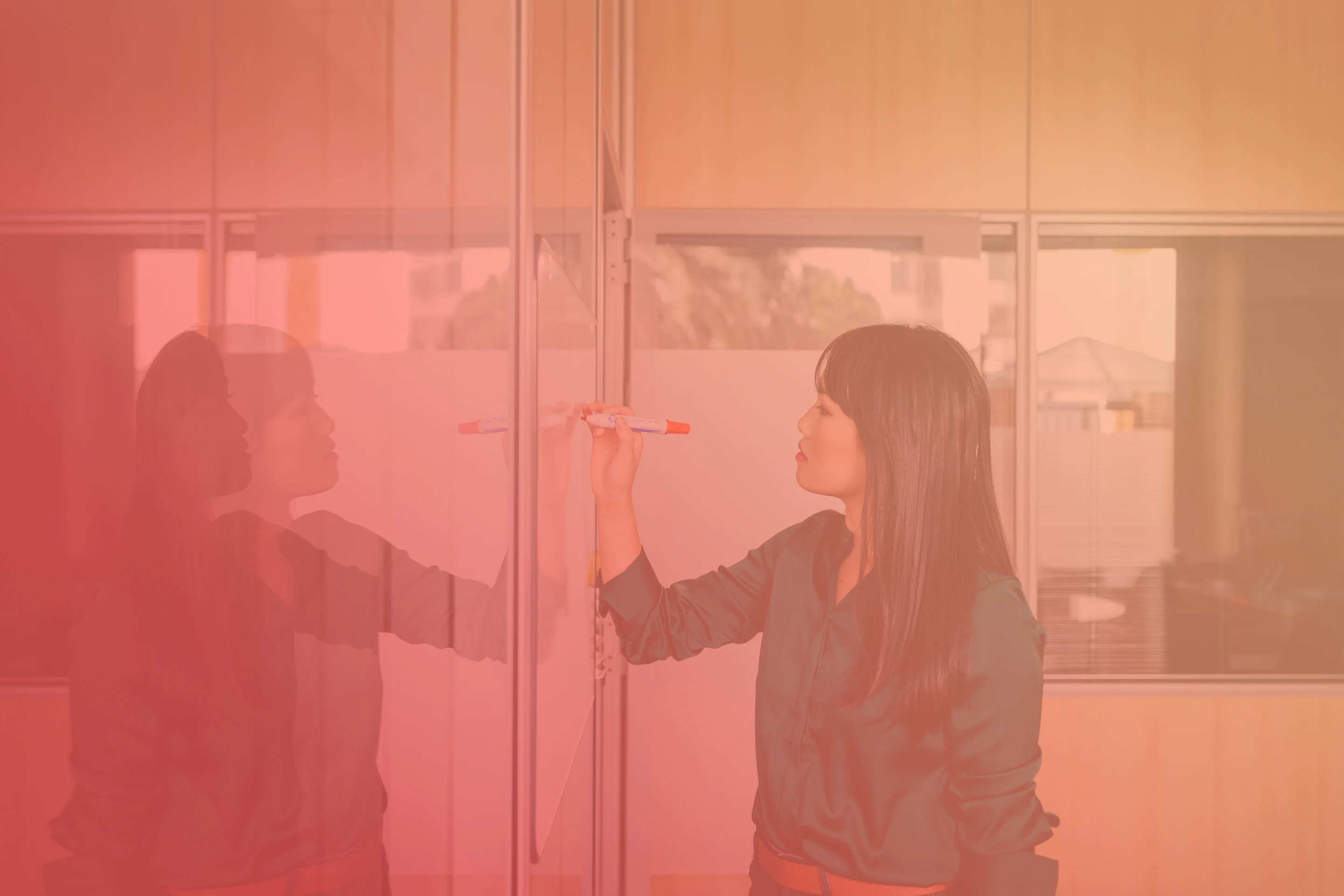 Professional female in business attire writing on Whiteboard