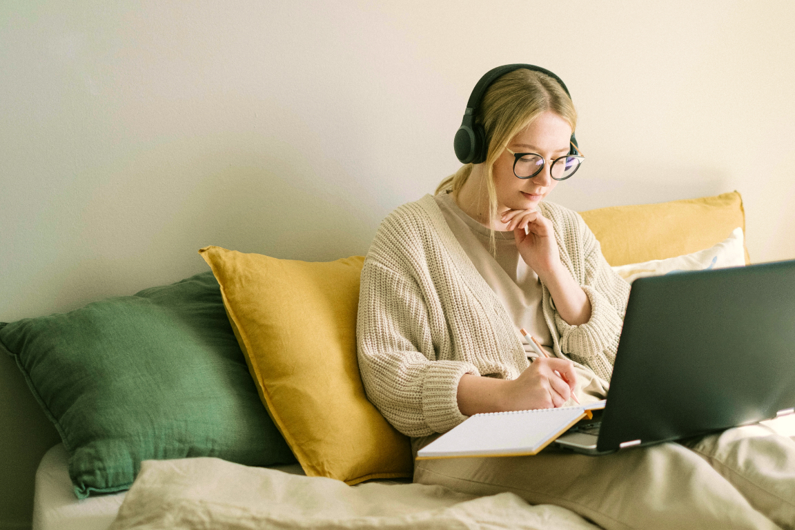 Woman working remotely participating in a video conference and taking notes