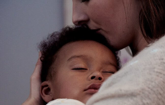 Madre con figlio che dorme tra le sue braccia