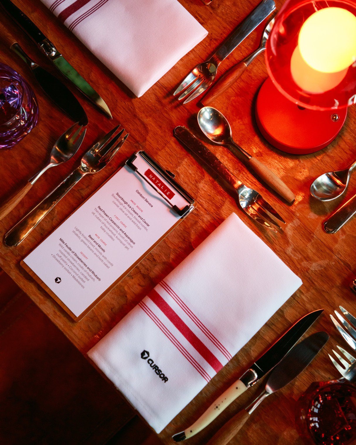 Figure 06. A personalized place setting and embroidered Cursor napkin make the detail worth photographing. "NATALIE" is visible on the setting; it is not used to identify a face or prove a full name. Supplied photo set, page 7 [10].