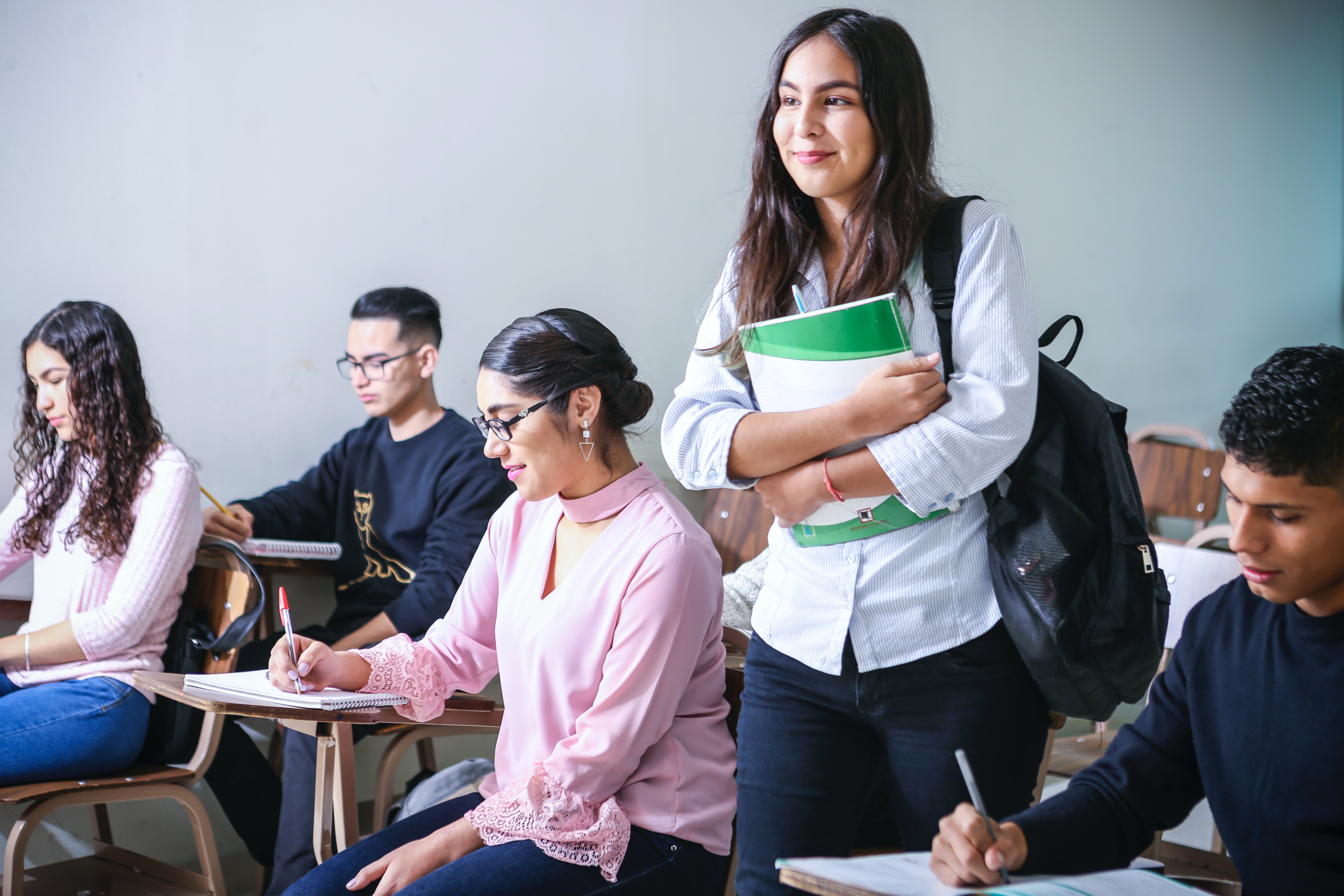 Young woman holding books in classroom - Photo by Javier Trueba via Unsplash