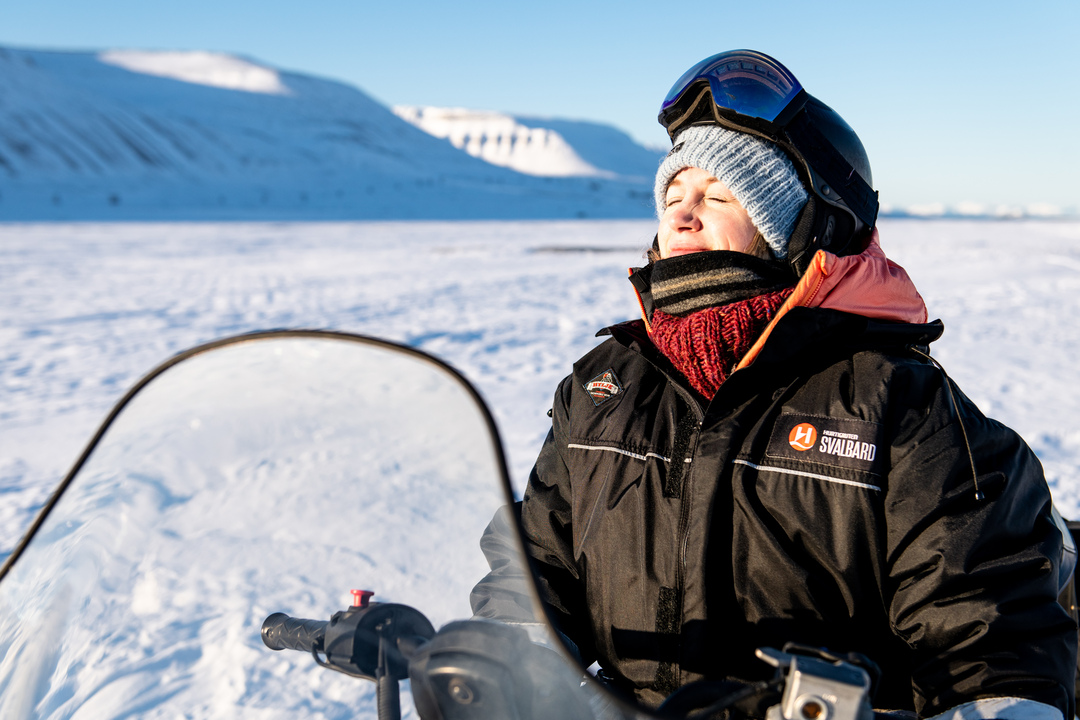 Happy guest on a snowmobile tour smiling in the sun