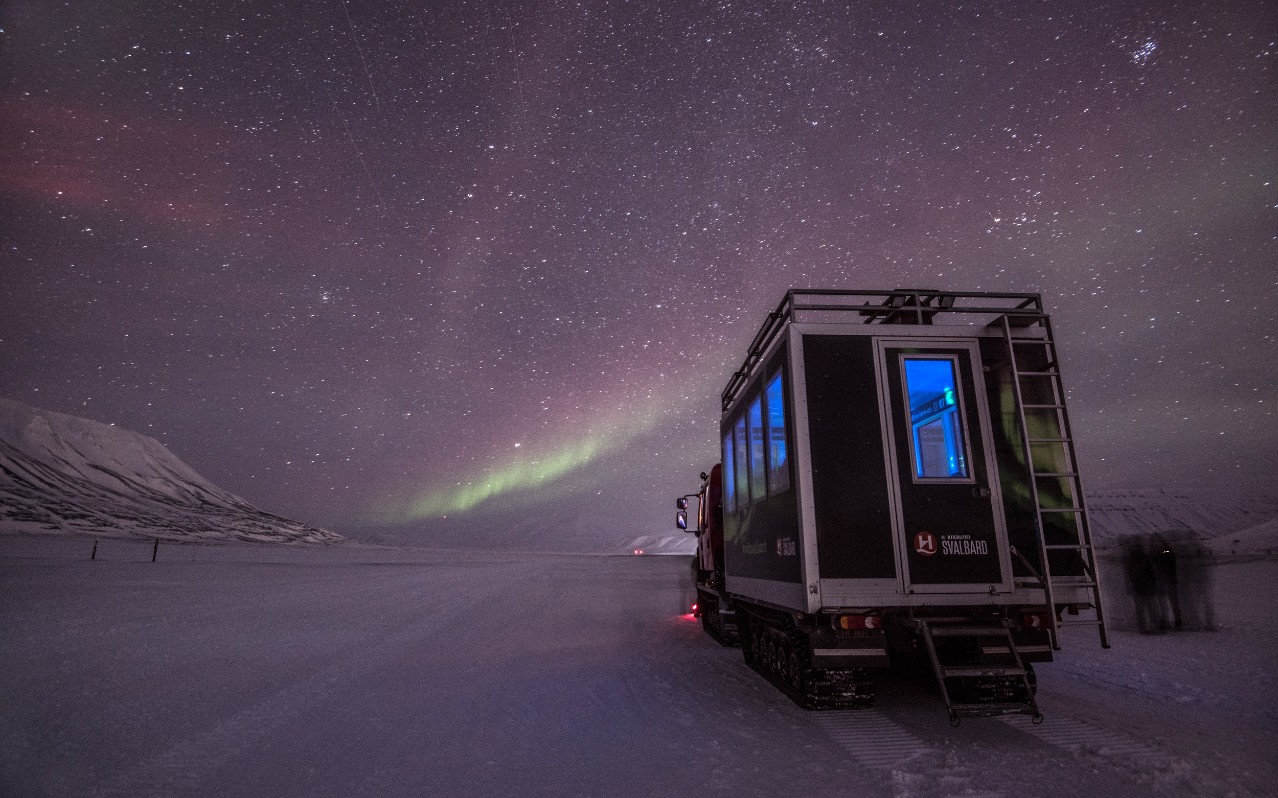 The Green and Red lights of the Aurora over a snowcat in Svalbard, Norway. Photo Credit: Agurtxane Concellon