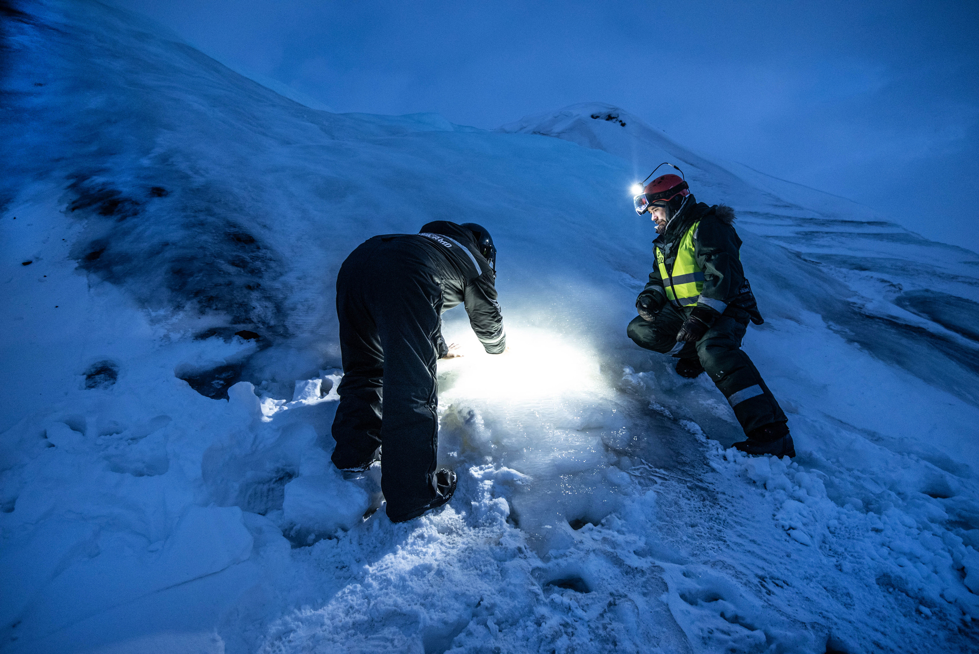 Guide and guest looking at ice together in the dark