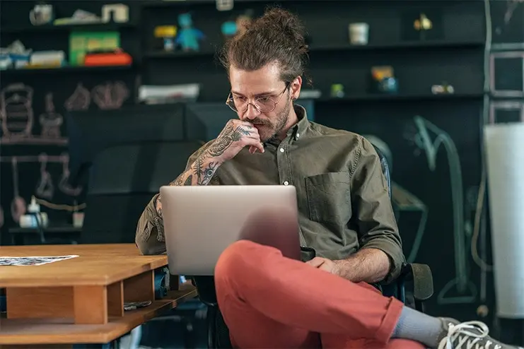 man-with-tattoos-looking-at-his-laptop