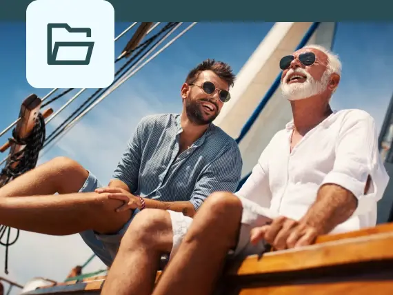 Photo of two men seated on a sailboat, smiling, with a folder icon overlay in the upper left corner.