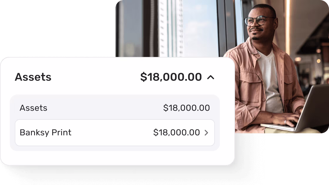 Man working on laptop with Quicken Simplifi assets screen displaying total assets of $18,000, including manually tracked Banksy Print