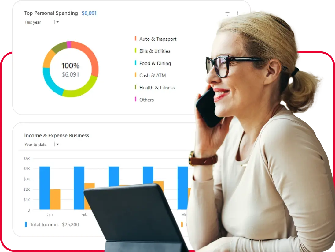 Woman wearing glasses smiles while talking on a phone at a laptop, with finance dashboards showing spending categories and income vs. expenses charts in the background.